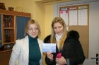 Travelnews.lv redaktore Kristīne Indriksone (no kreisās) pasniedz balvu konkursa laimētājai Kristīnei Grīnbergai, kas Travelnews.lv sociālajā tīklā se 2
