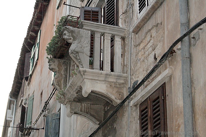 Ēkas papildina īpaši dekorēti balkoni, logu vai durvju velves, kas piešķir tām senatnes noskaņu 65573